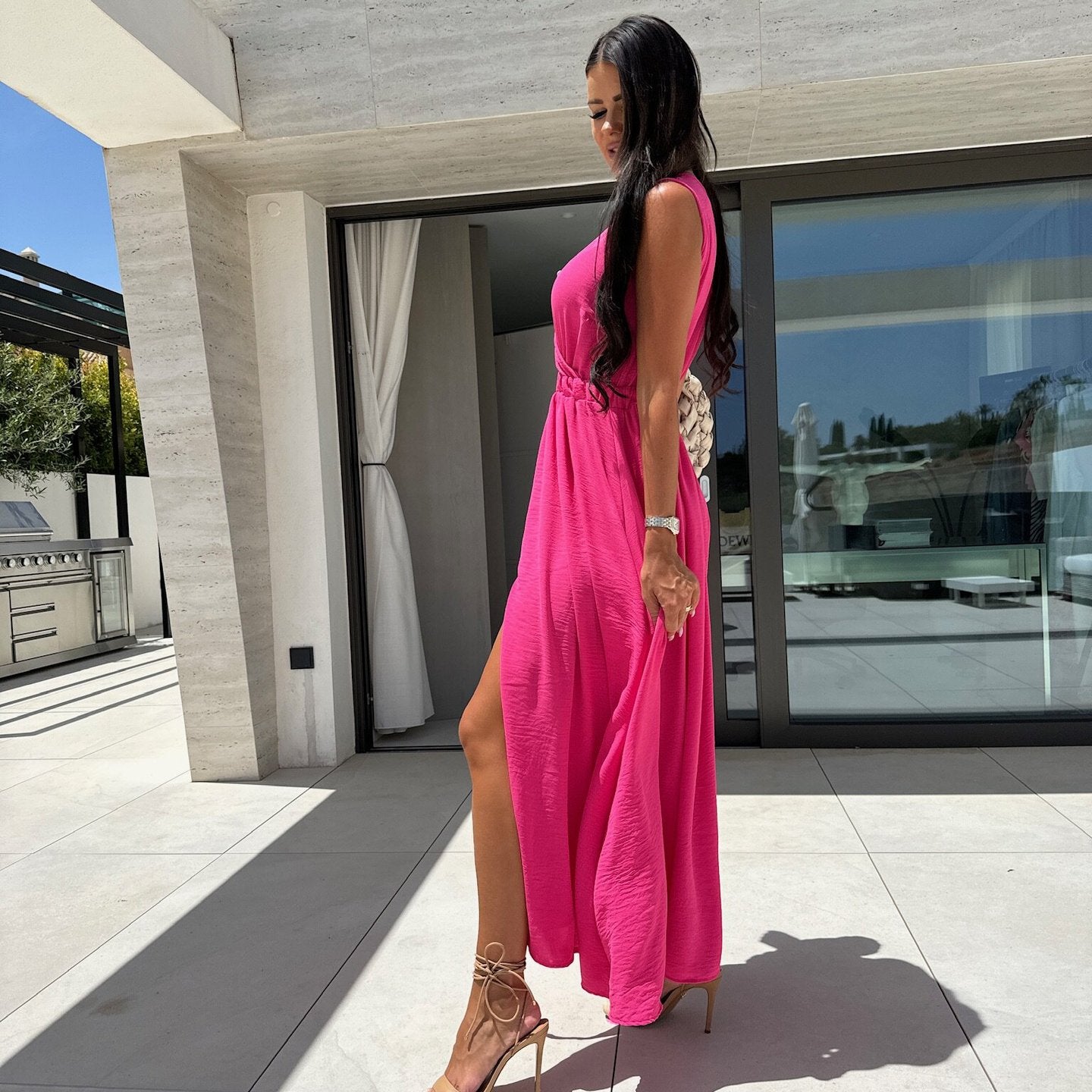 Woman in a pink maxi dress with strappy heels emphasizing elegant fashion and ملابس style