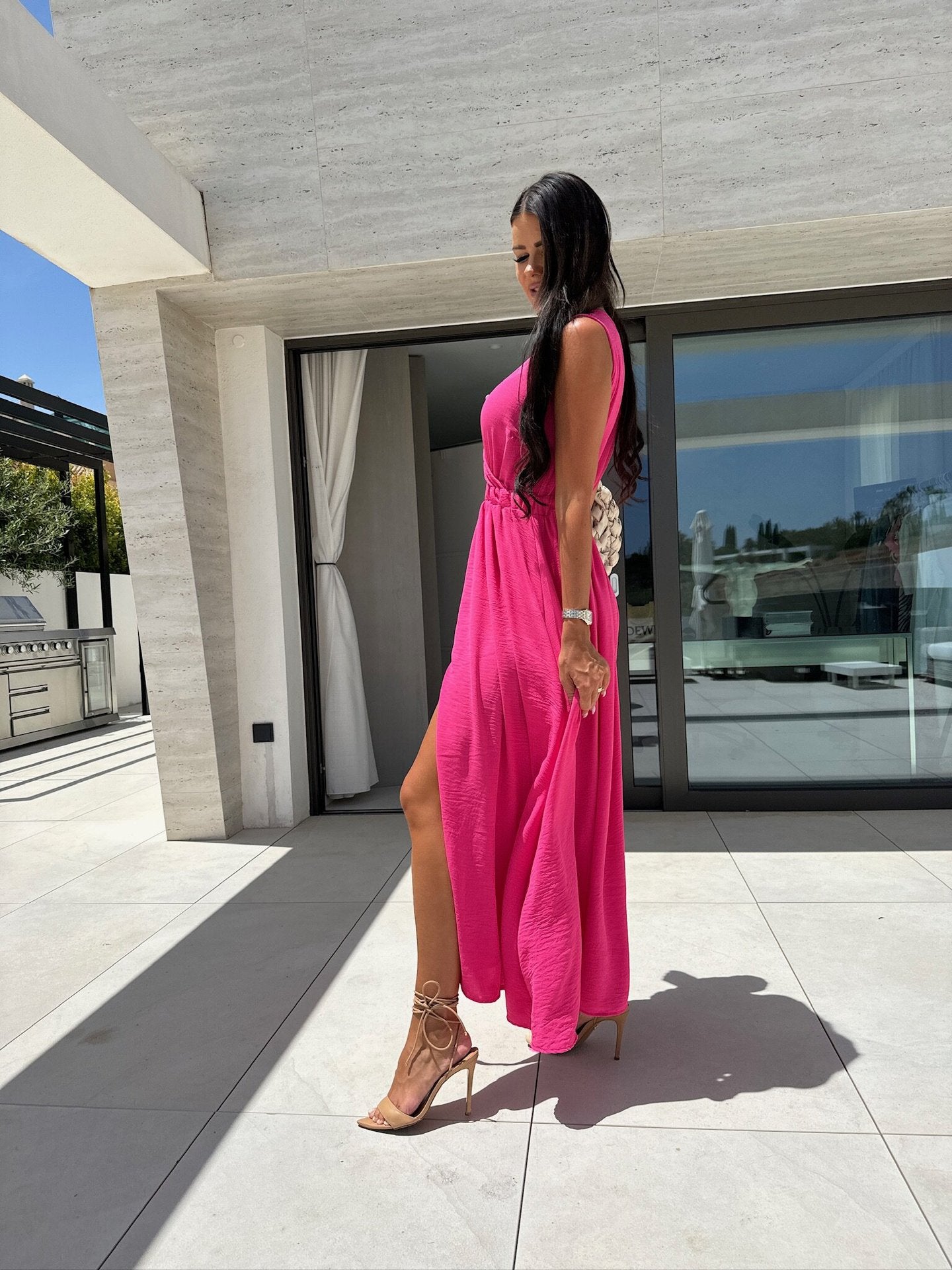 Woman in a pink maxi dress with strappy heels emphasizing elegant fashion and ملابس style