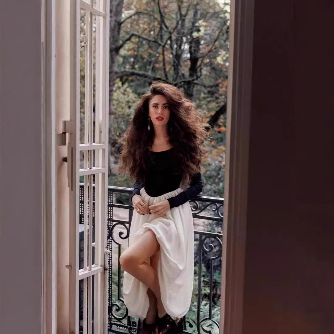Woman in Elegant Hepburn Dress by French doors, showcasing trendy fashion and style