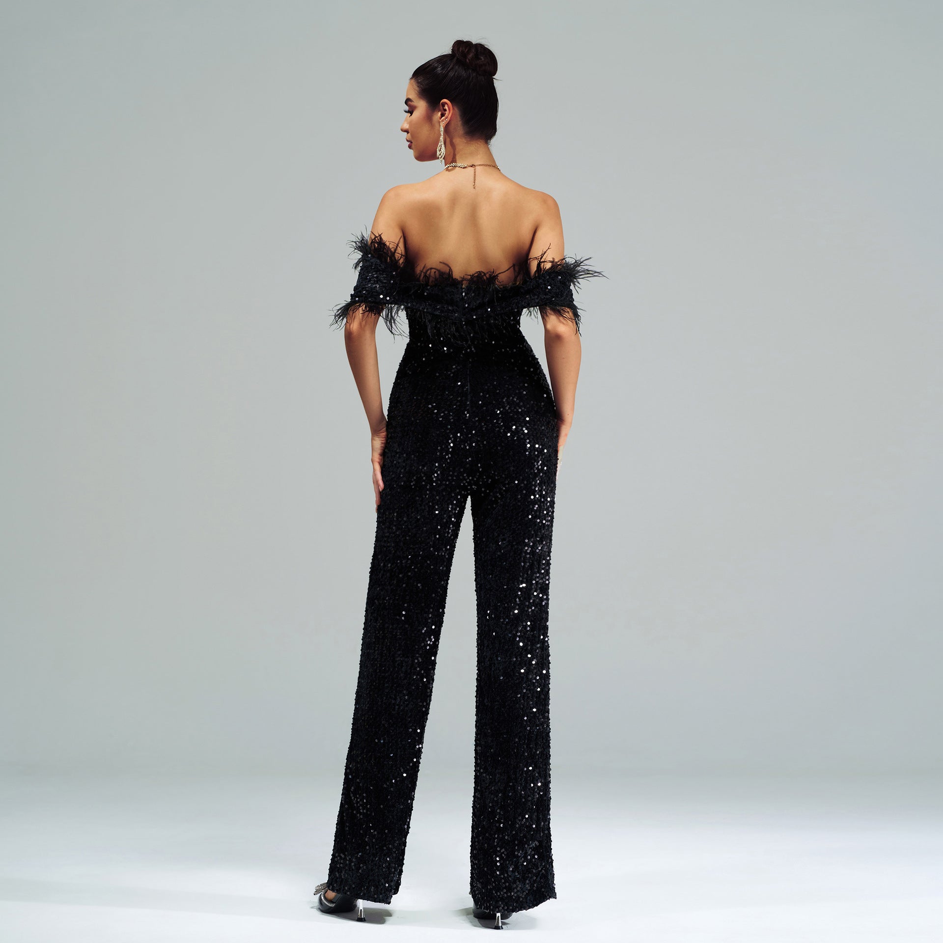 Elegant sequin-covered black jumpsuit with feather trim showcasing high-end fashion style
