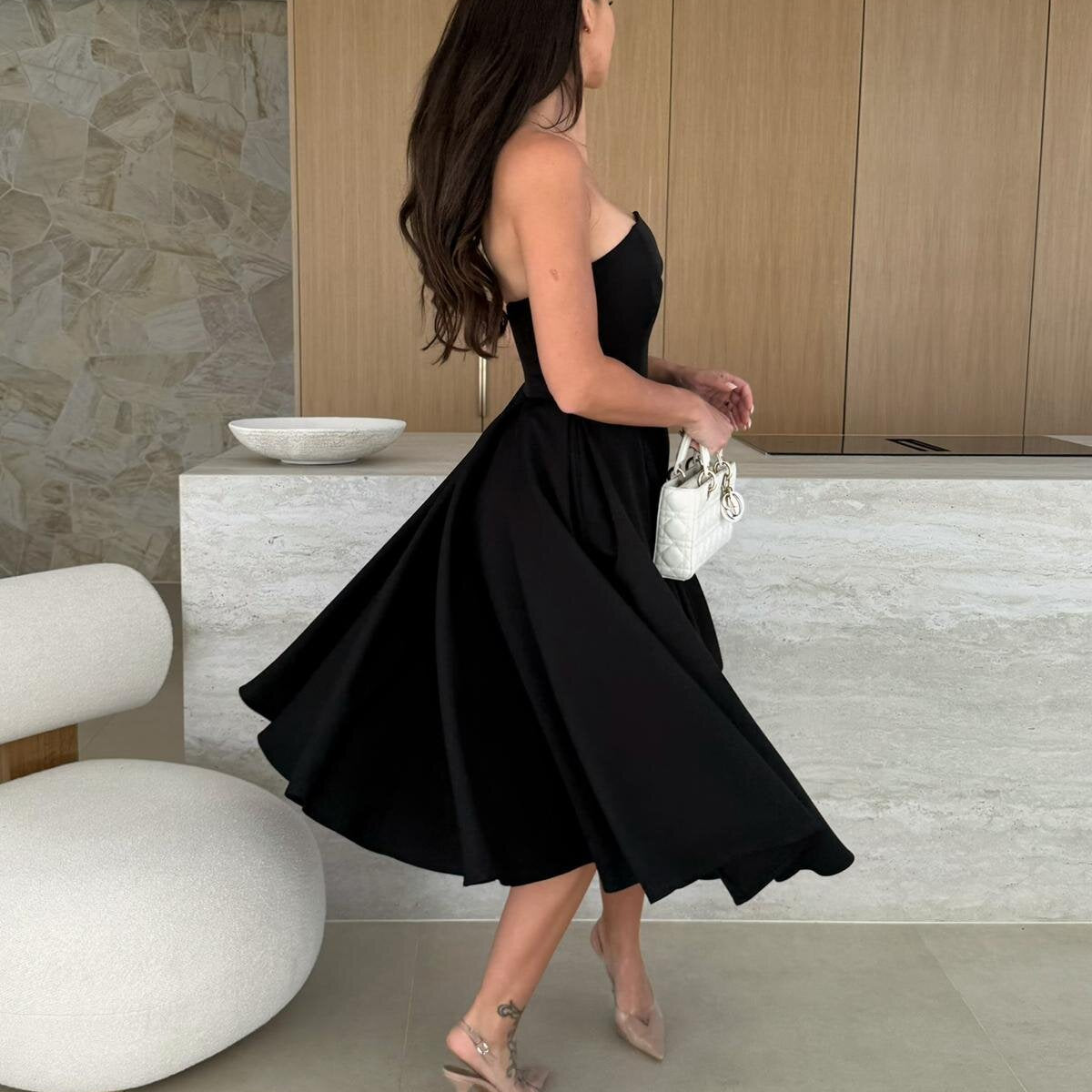 Woman in a black strapless dress, showcasing the elegance of Gorgeous Midi Dress fashion