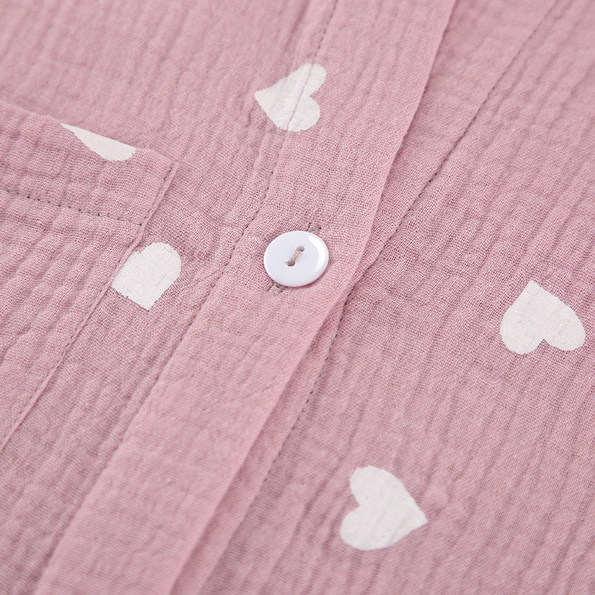 Pink crinkle-textured fabric with white heart patterns and a white button in pajamas set