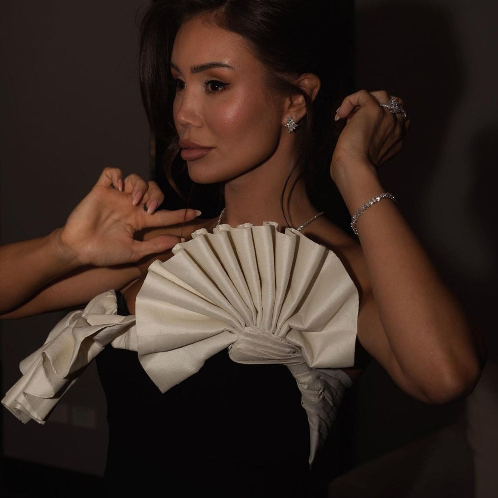 Elegant white pleated bow detail on a black strapless dress in fashion ملابس