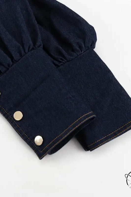 Dark blue denim shirt cuff with three gold buttons on fashionable dress