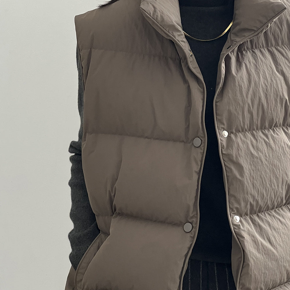 Taupe quilted puffer vest with snap buttons over black top in Langry fashion ملابس