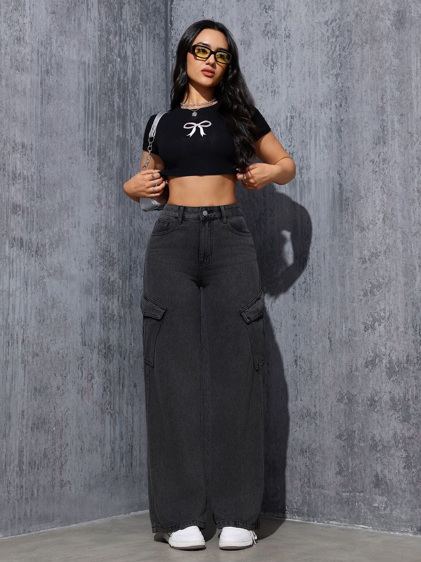 Woman in black crop top and wide-leg cargo jeans showcasing trendy gray black fashion style