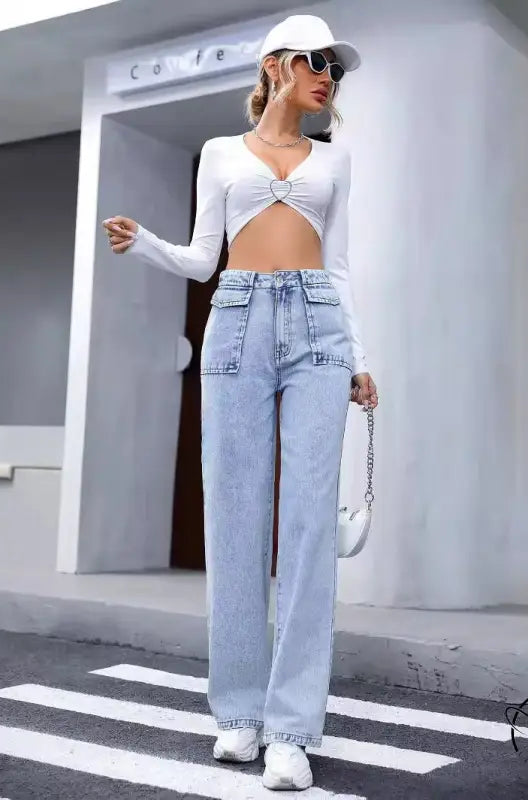 Woman in langry denim trousers, white crop top, cap, bag and sneakers
