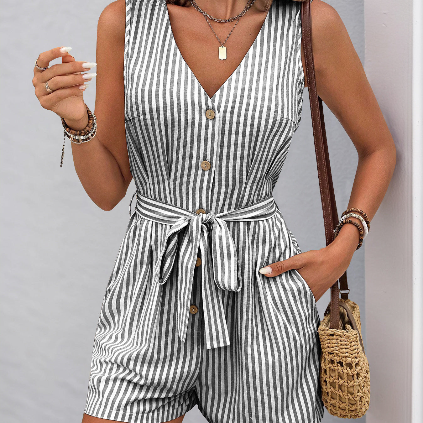 Sleeveless striped romper with v-neck, buttons, pockets, and waist tie for summer fashion