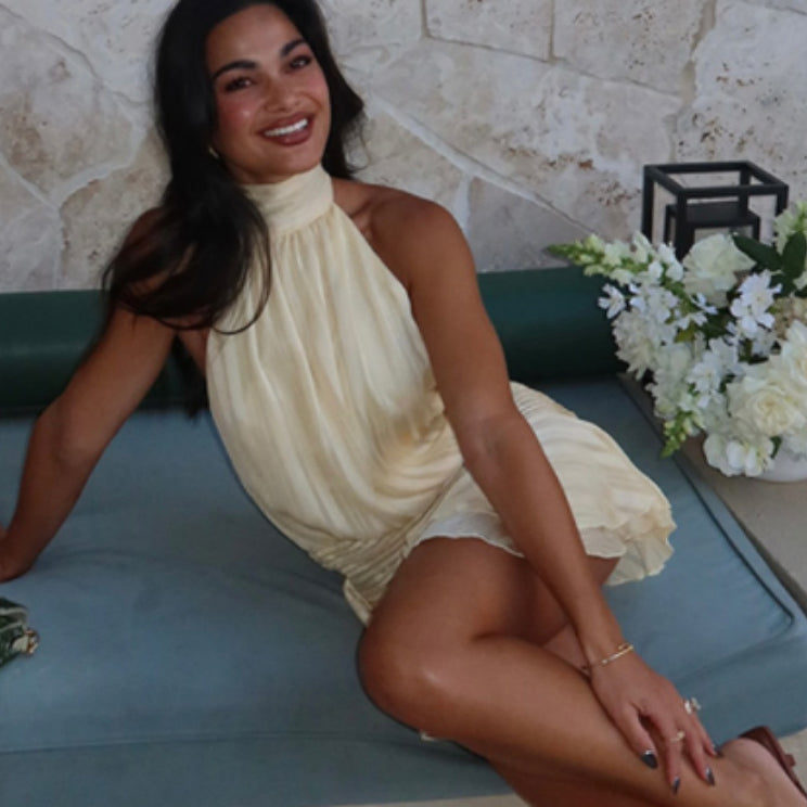 Woman in a yellow halter dress, showcasing the latest fashion in ملابس with a stunning backless design