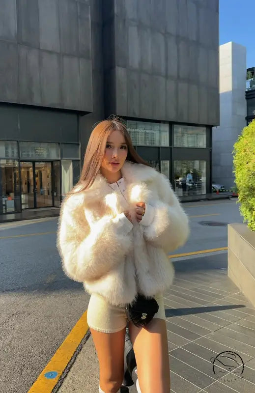 Short loose casual faux fur coat by Langry with cream color, black trim, and pockets