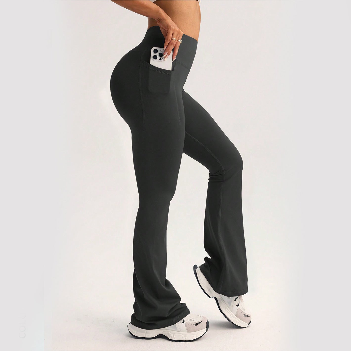 Black langry high-waisted flared yoga pants with side pocket holding white smartphone