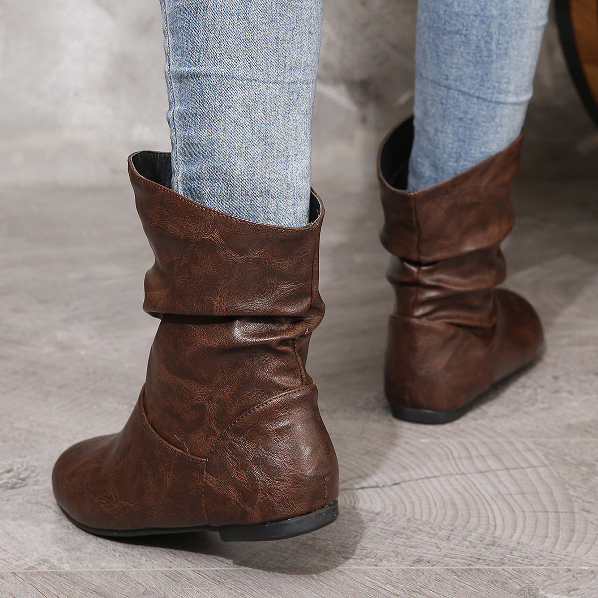 Brown leather slouch boots paired with light blue jeans, showcasing low heel faux leather boots