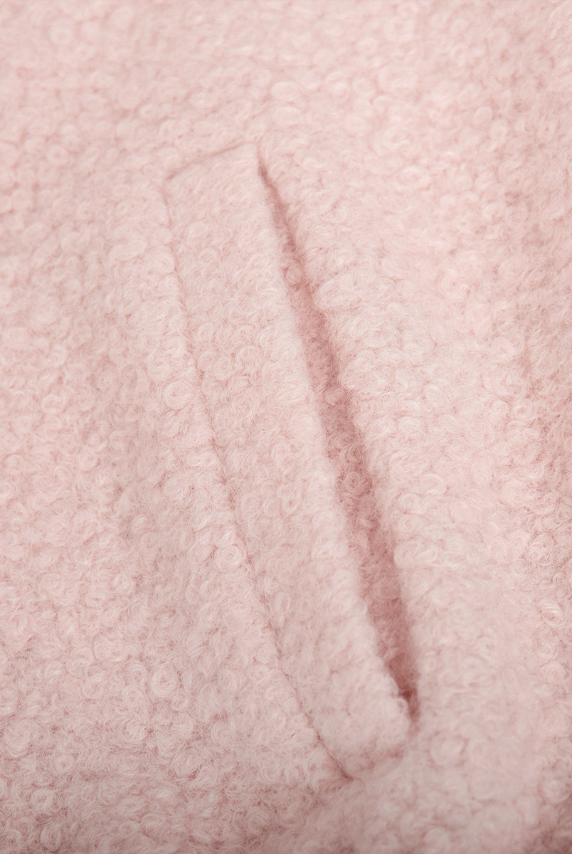 Pink short furry coat showcasing pink bouclé fabric with pocket detail