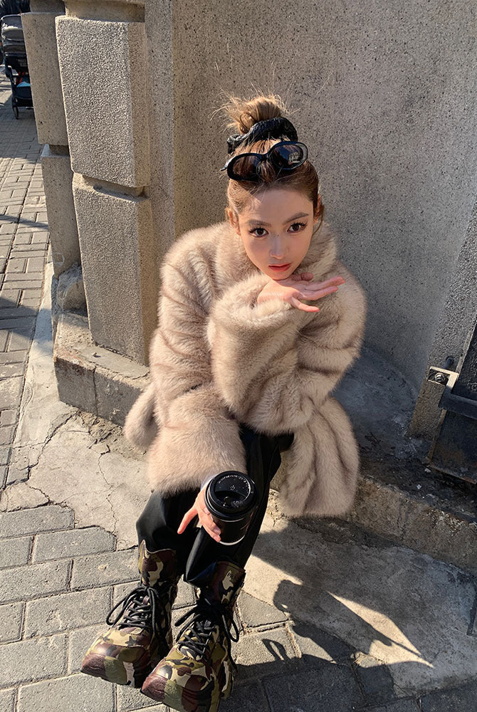 Beige faux fur Langry fashion jacket with black boots and bun