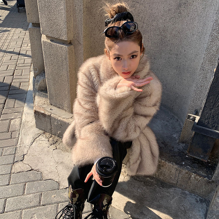 Beige faux fur Langry fashion jacket with black boots and bun