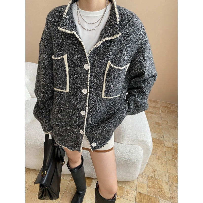 Fashionable double pocket loose knitted sweater coat in gray boucle with white piping, layered necklaces, and black boots