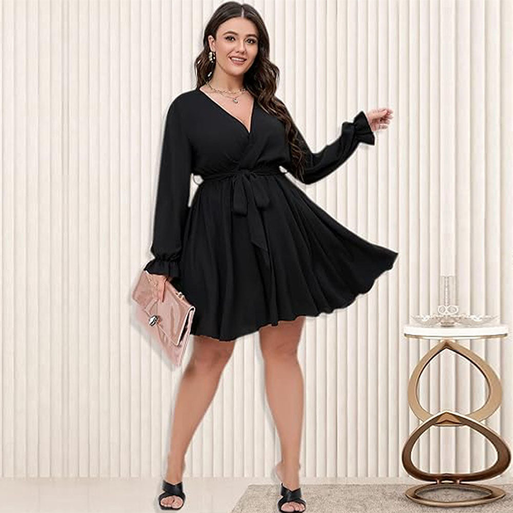 Woman in black winter office midi dress with V-neck and tie waist holding pink clutch