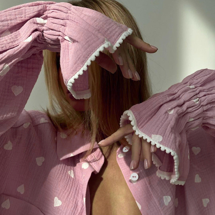 Pink long-sleeved pajamas set with white heart patterns and ruffled trim for fashionable comfort