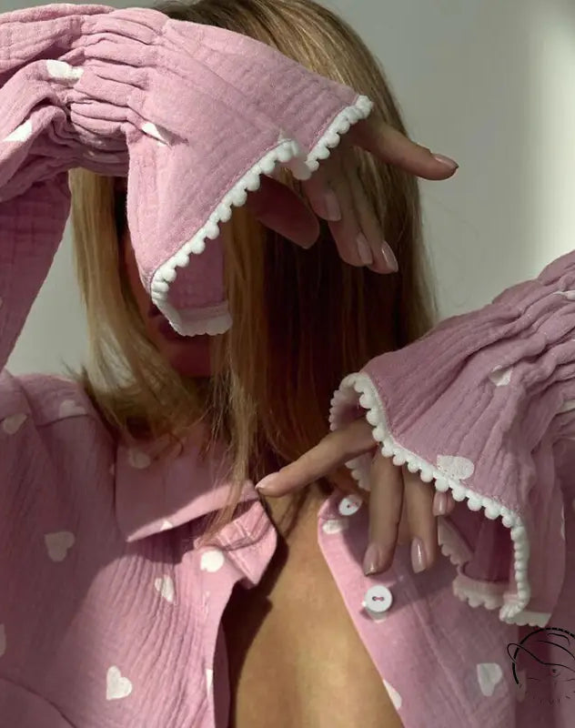 Pink long-sleeved pajamas set with white heart patterns and ruffled trim