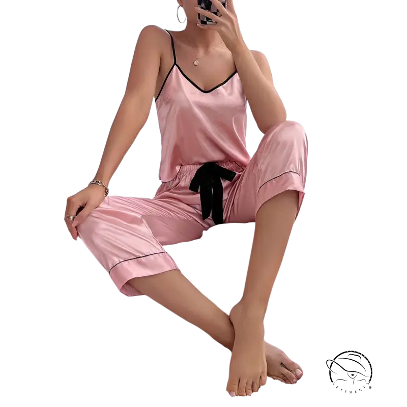 Pink satin pajama set with black trim, bow, and black eye mask