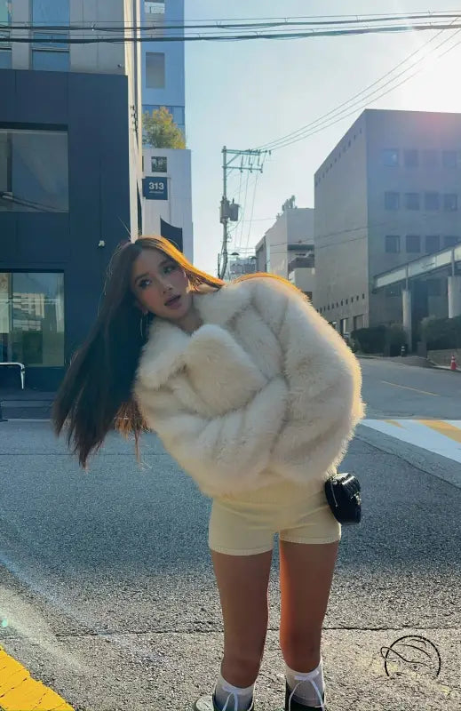 Short loose casual faux fur coat in cream with black trim and pockets by Langry