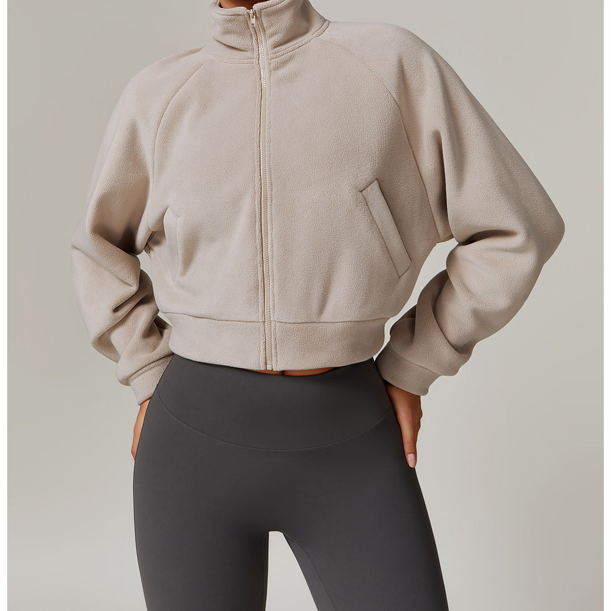 Beige cropped zip-up sweatshirt with high collar and gray leggings for stylish fitness