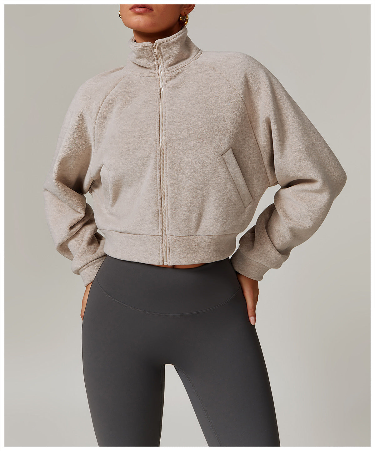 Beige cropped zip-up sweatshirt with high collar and gray leggings for stylish fitness