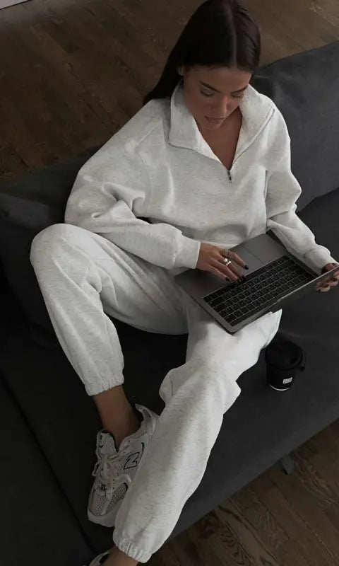 Woman in gray half zipper autumn winter fleece lined sweatsuit using laptop