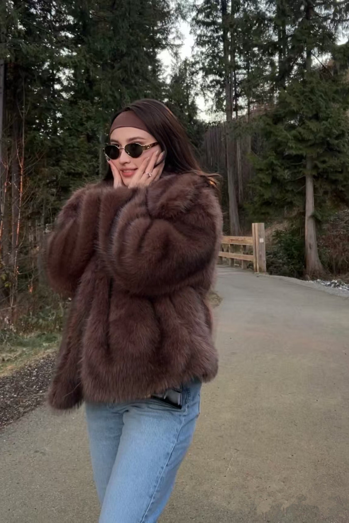 Elegant faux fur fox coat in brown black with oversized collar, paired with light blue jeans