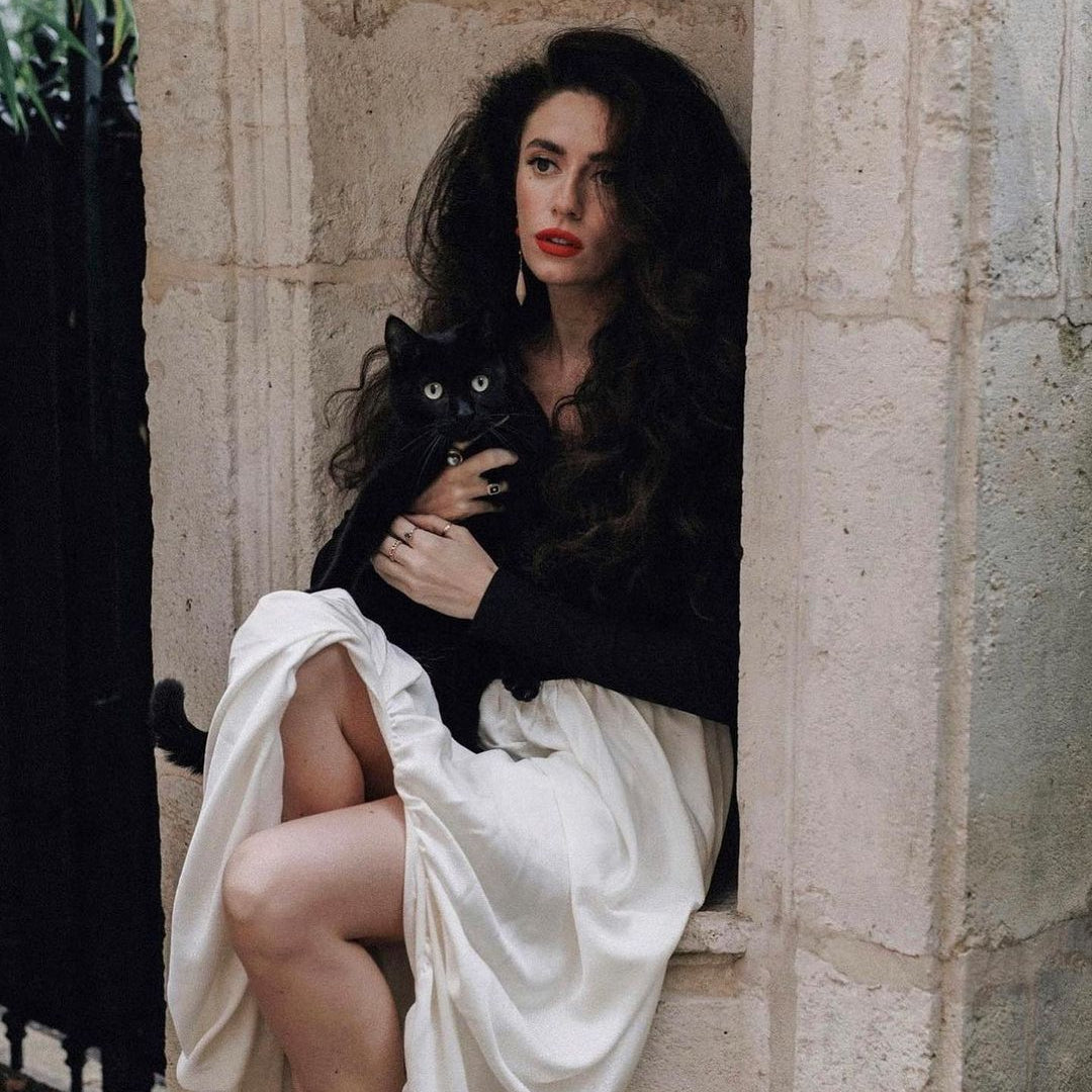 Person in Elegant Hepburn Dress with black top and white skirt holding a black cat