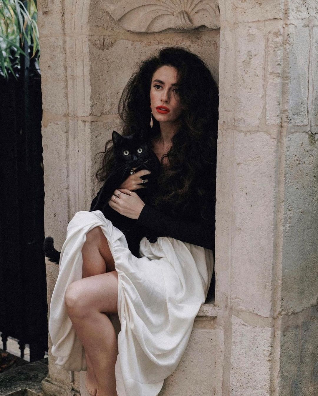 Person in Elegant Hepburn Dress with black top and white skirt holding a black cat