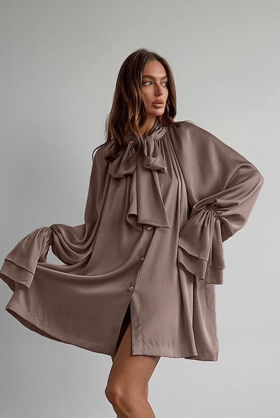 Flowy taupe satin dress with oversized bow and billowing sleeves for elegant fashion