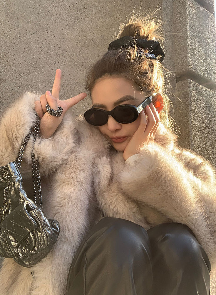 Cream faux fur coat with black sunglasses and silver chain bag