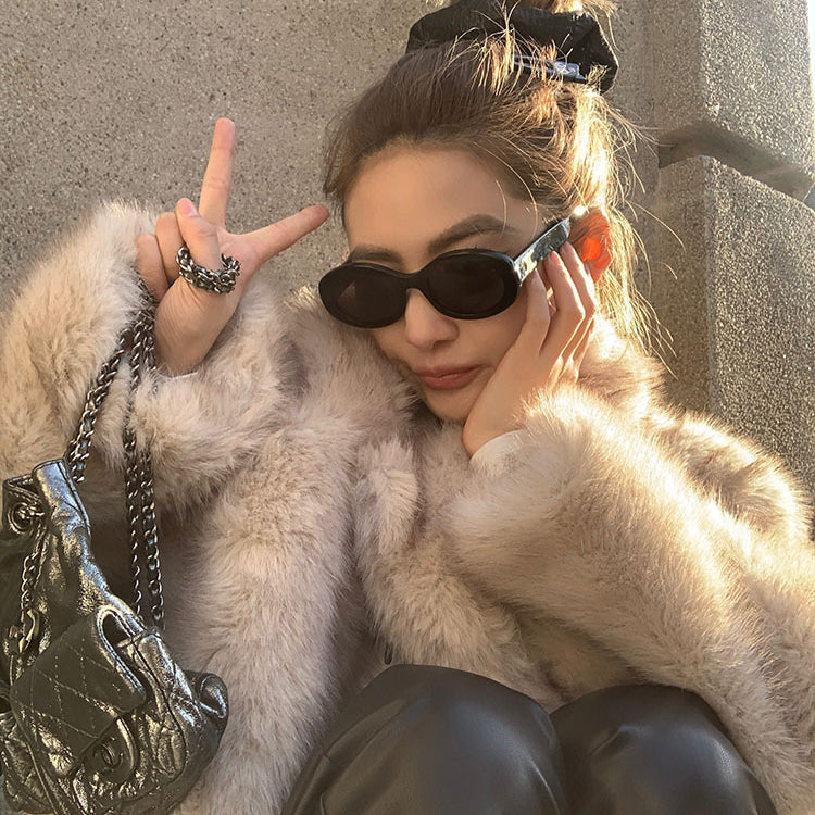 Cream faux fur coat with black sunglasses and silver chain bag