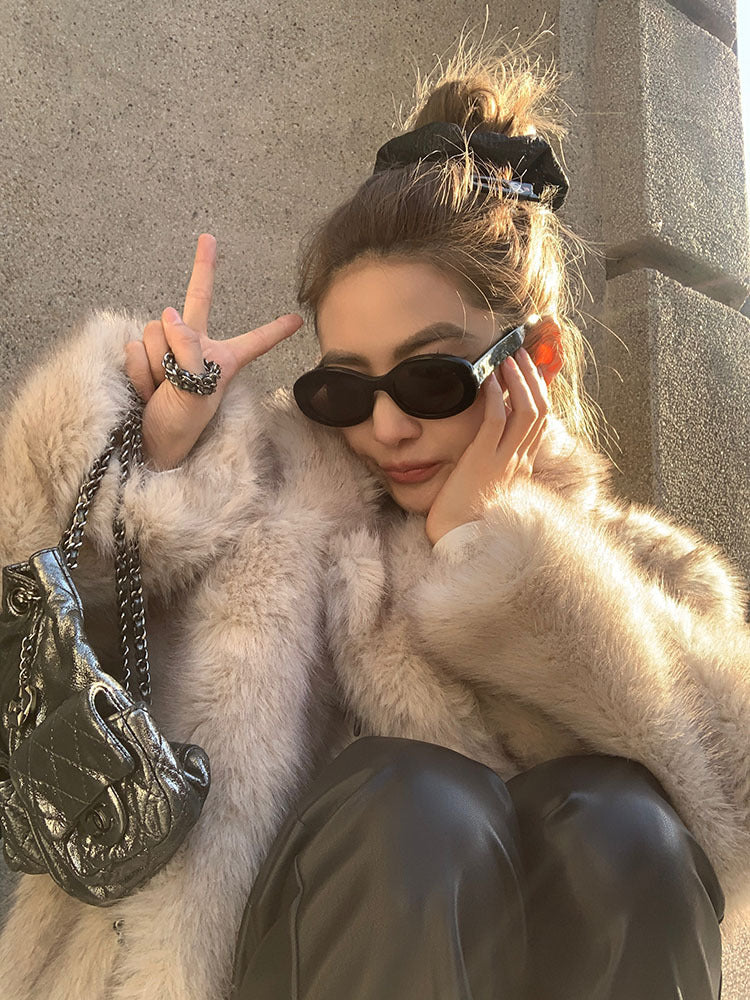 Cream faux fur coat with black sunglasses and silver chain bag