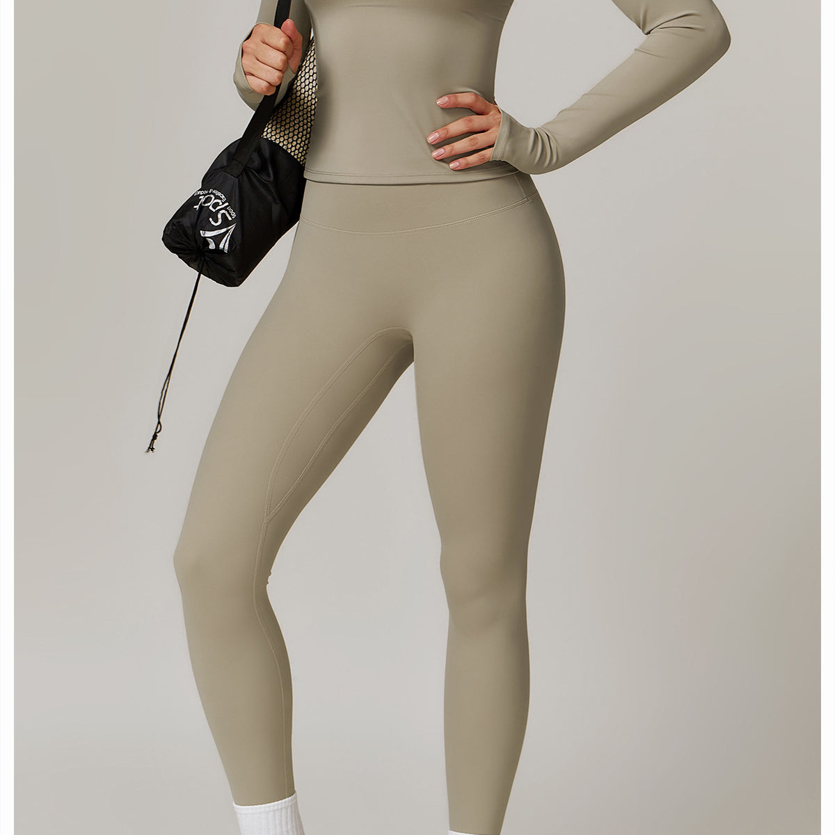 Beige long-sleeved langry athletic bodysuit with white sneakers and black handbag