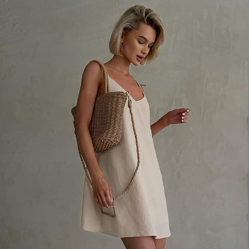 A woman in casual linen slip dress with woven straw bag showcasing summer fashion and ملابس