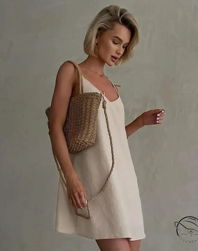 Woman in casual backless cotton home wear slip dress with straw bag