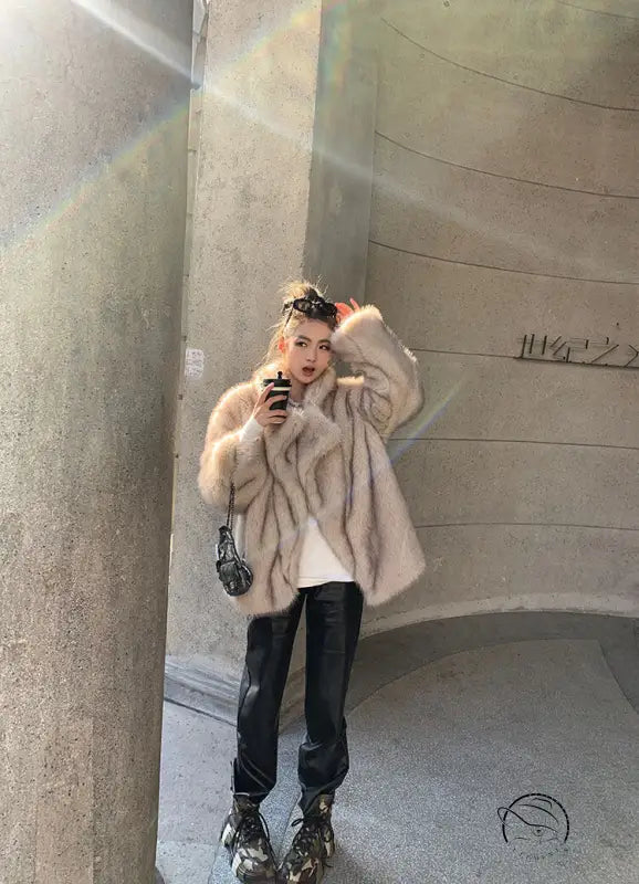 Beige faux fur oversized coat with black leather accents and floral headband