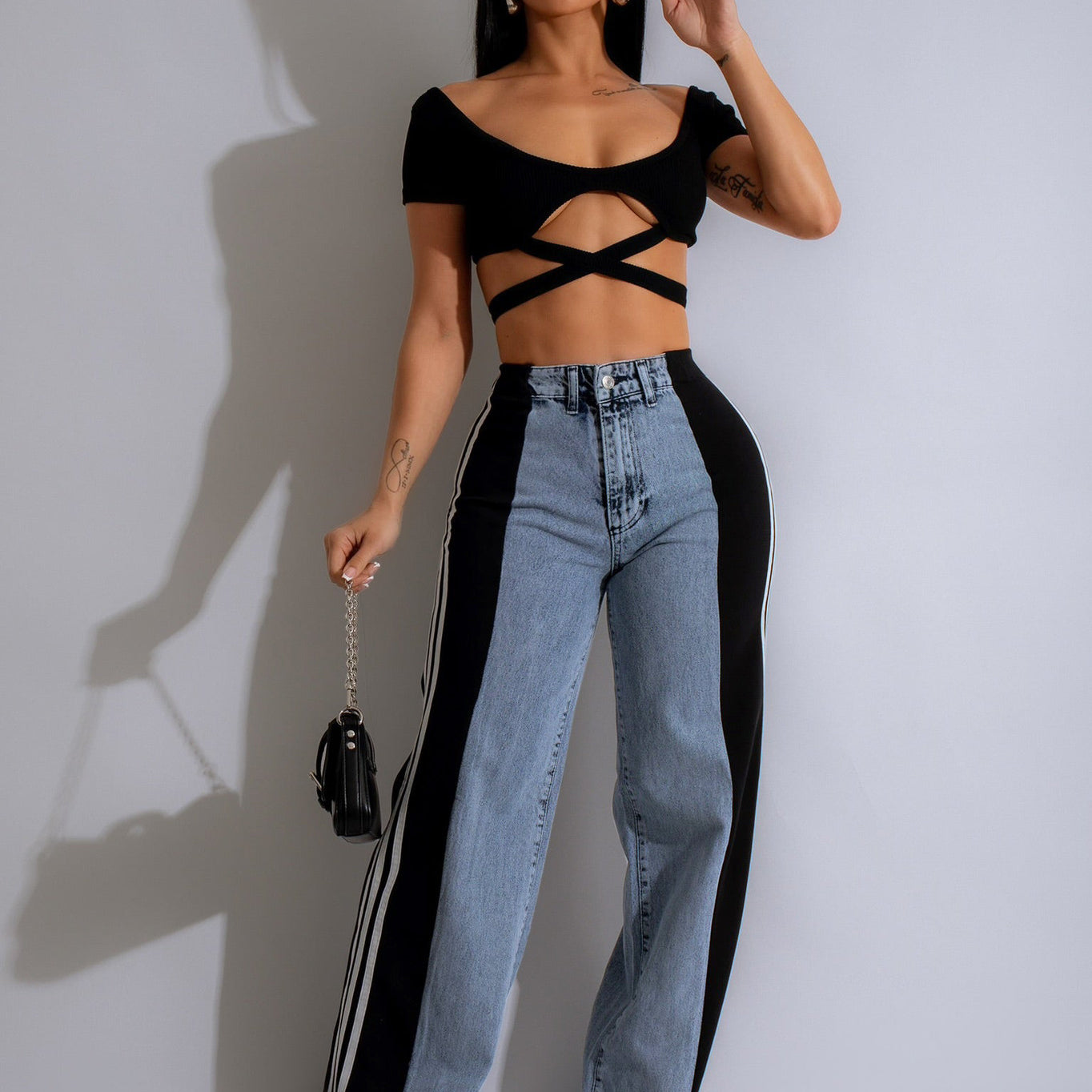 Two-tone jeans with light denim front and black sides, paired with a black crop top