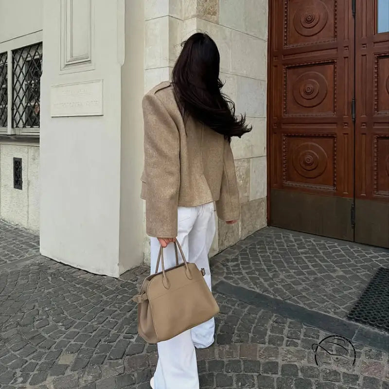 Beige textured handbag with dual handles on large collared short coat