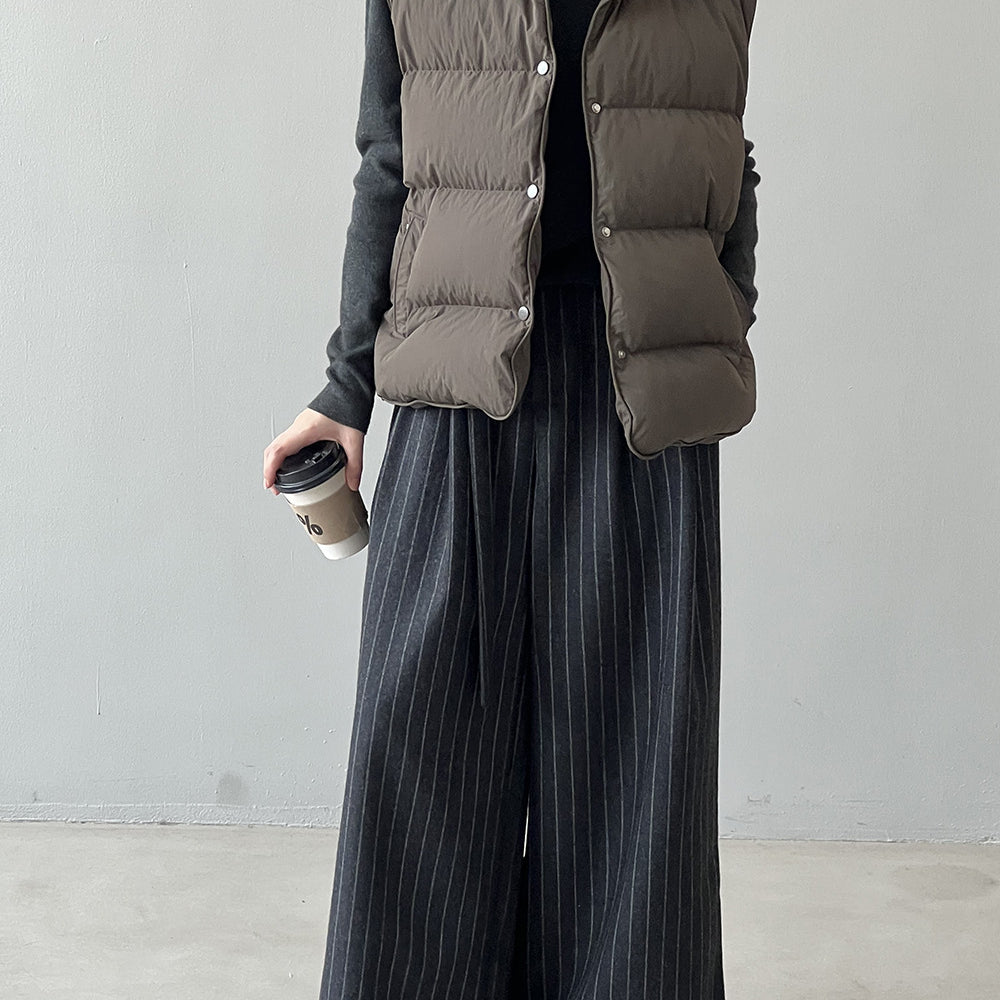 Taupe puffer vest styled with black turtleneck and pinstriped pants, perfect for fashion ملابس
