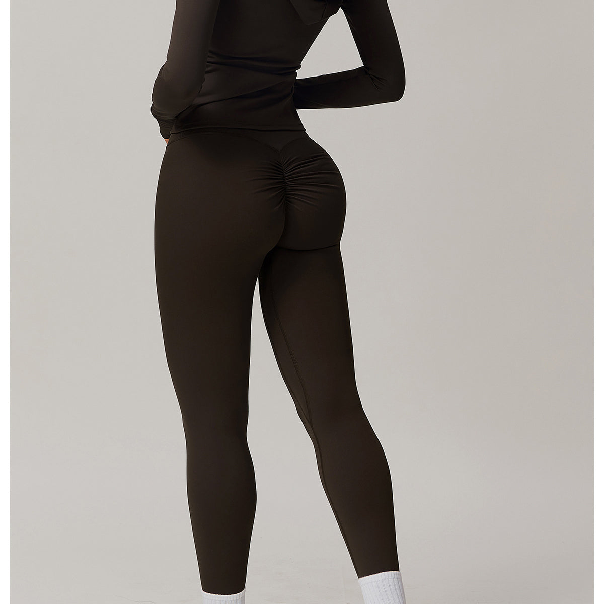 Black athletic bodysuit with long sleeves, white socks, and sneakers for fashion enthusiasts