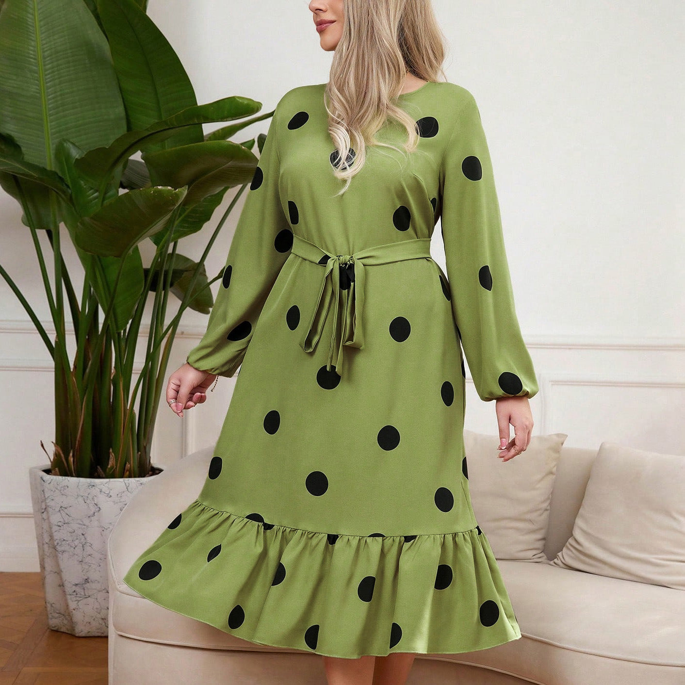 Woman wearing a vibrant lime green Lotus Leaf Dress with ruffled hem and black polka dots