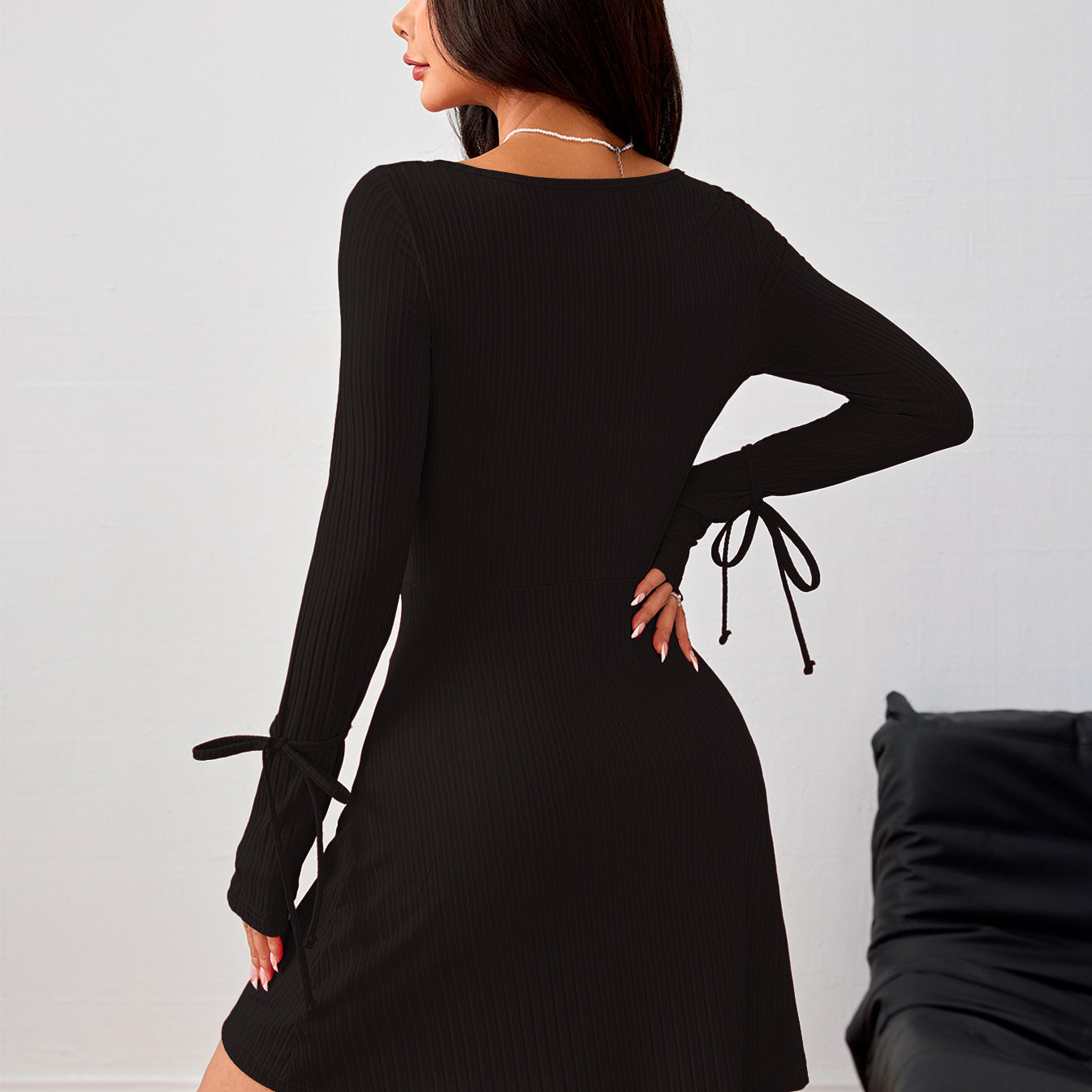 Black long-sleeved dress with side tie details, perfect for stylish fashion statements