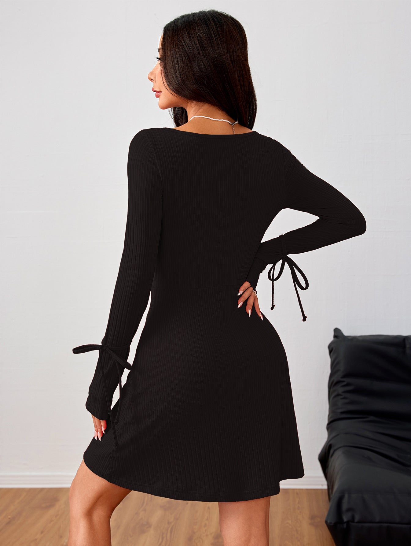 Black long-sleeved dress with side tie details, perfect for stylish fashion statements