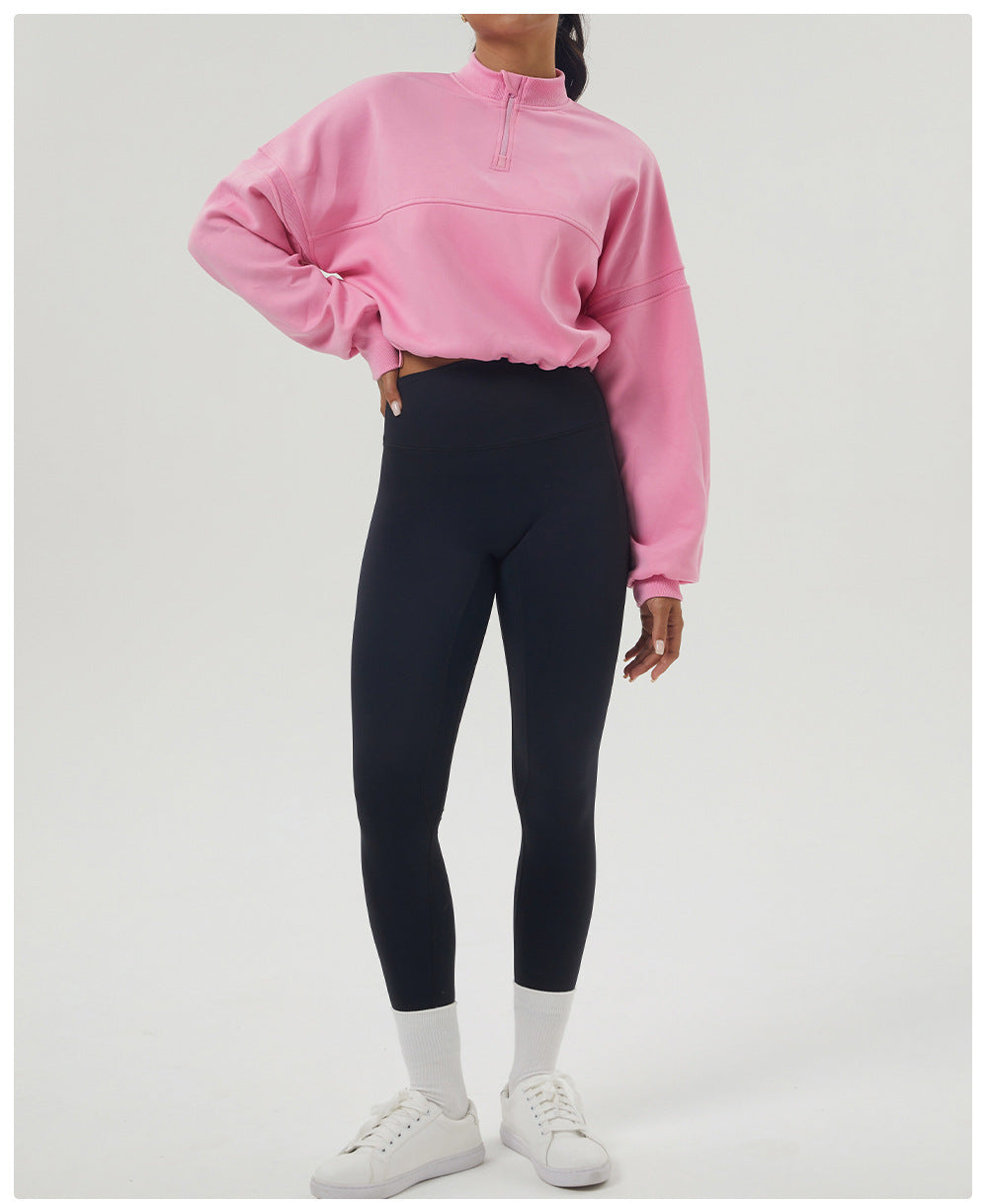 Woman in pink long sleeve sweatshirt and black leggings showcasing fitness fashion style