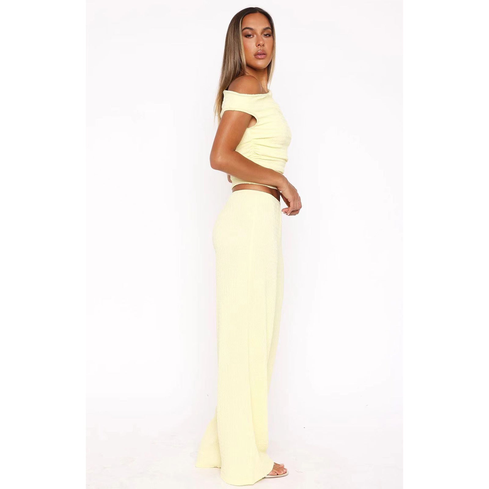 Woman in yellow off-the-shoulder top and wide-leg pants, stylish fashion ملابس set