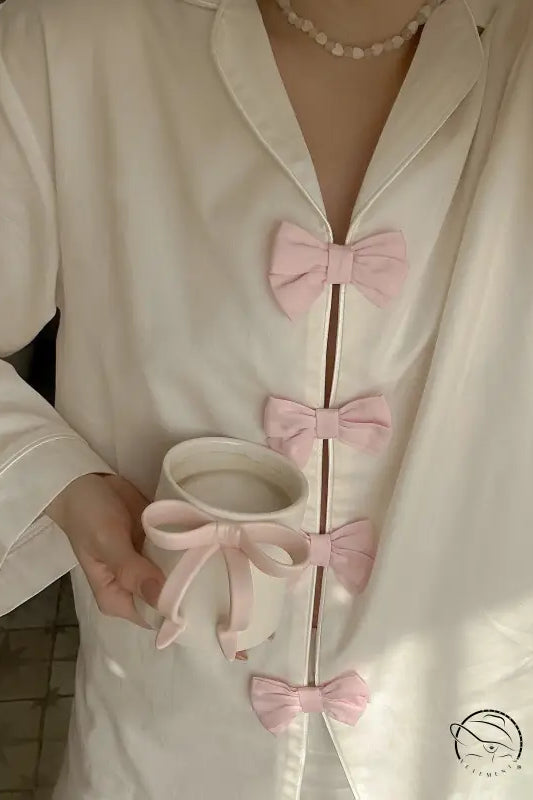 White silk langry fashion pajamas set with pink bow accents and pearl necklace