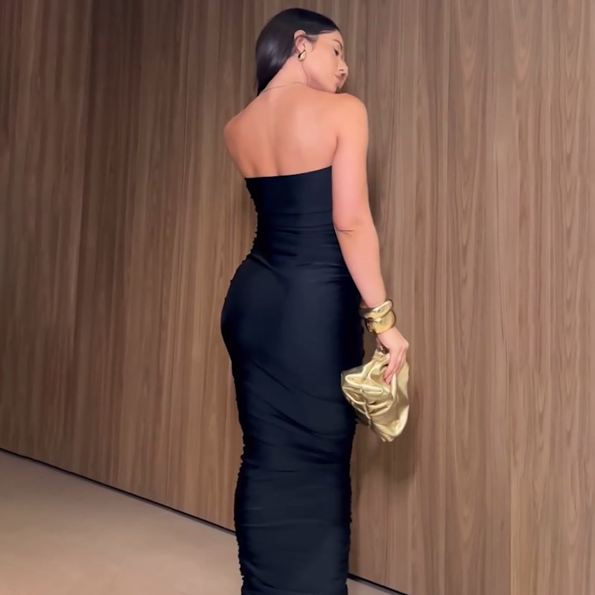 Elegant sleeveless black dress with gold accessories for a luxurious night out fashion look